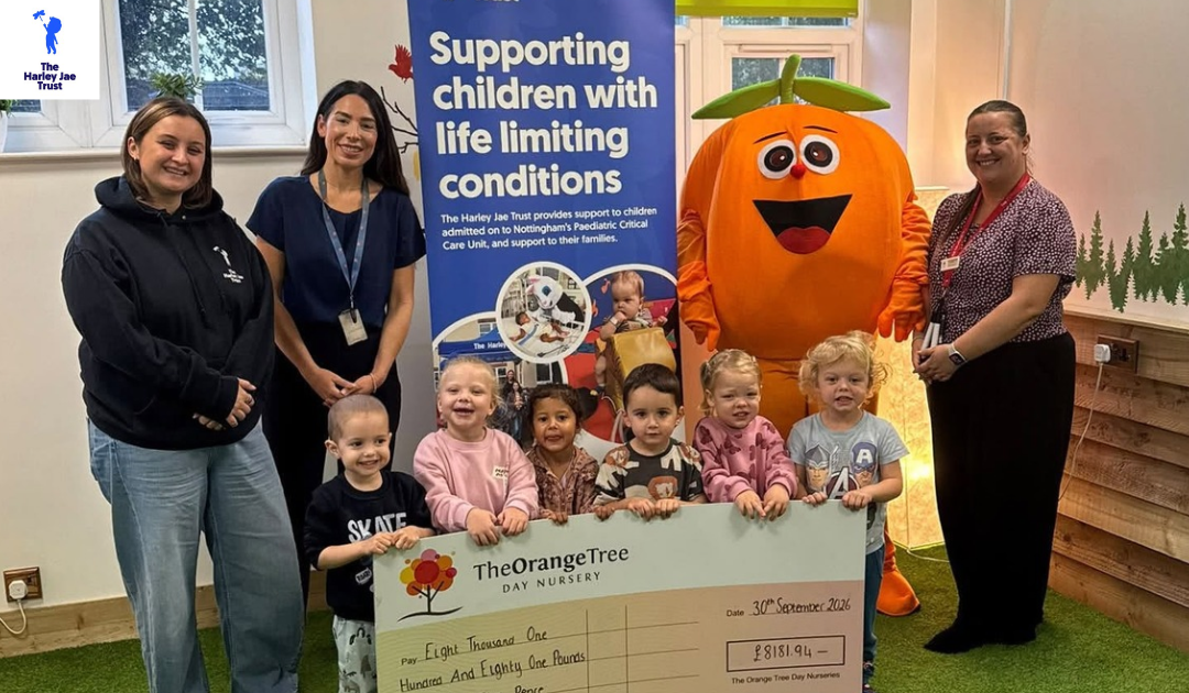 group of small children smiling to camera holding giant check with group of women teachers and an orange mascot during charity event