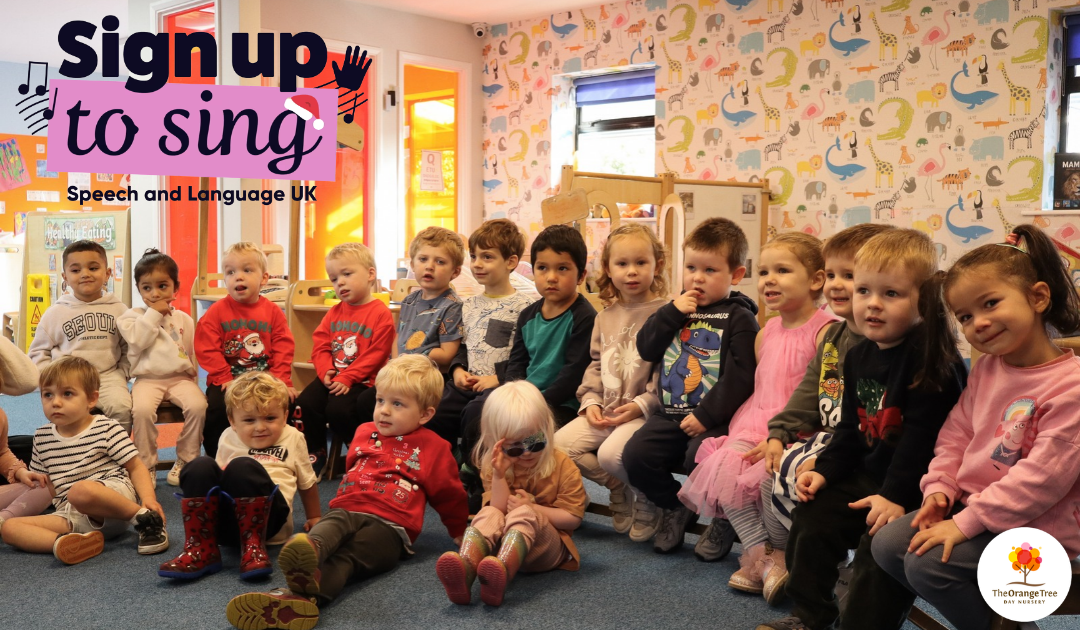 A group of young children sitting together on a bench at nursery in Derby, smiling, laughing, and sharing a happy moment during group activity time
